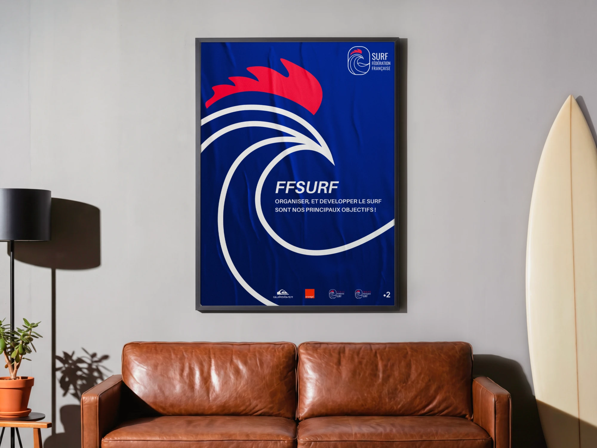 L'affiche de la fédération encadrée au-dessus d'un canapé en cuir, à côté d'une planche de surf